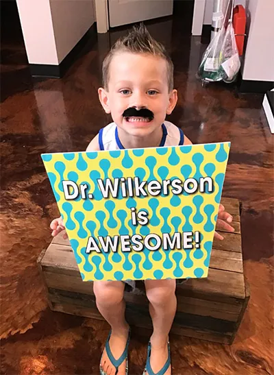 The Kid's Place patient holding up a 'Dr. Wilkerson is awesome!' sign